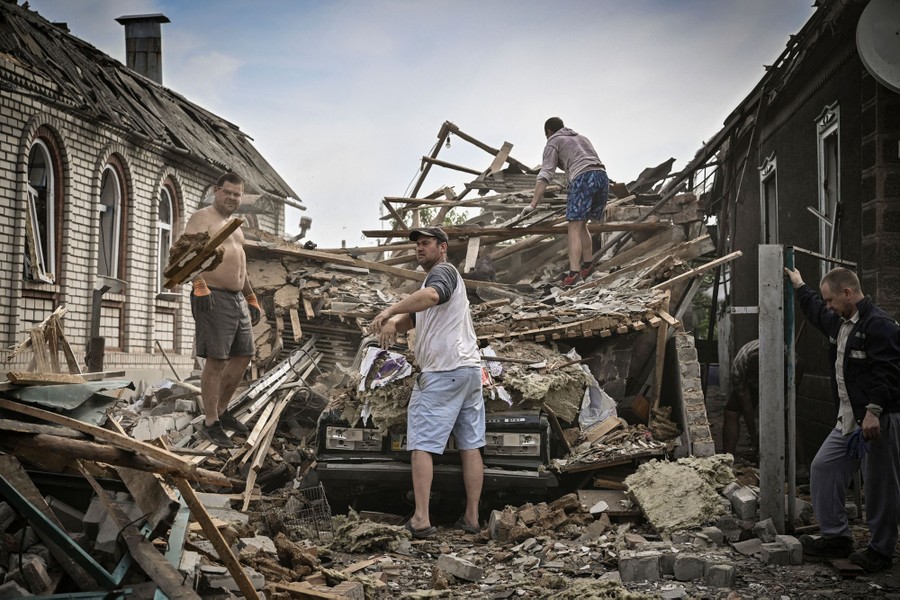 Four people work to remove debris from a garage and house.