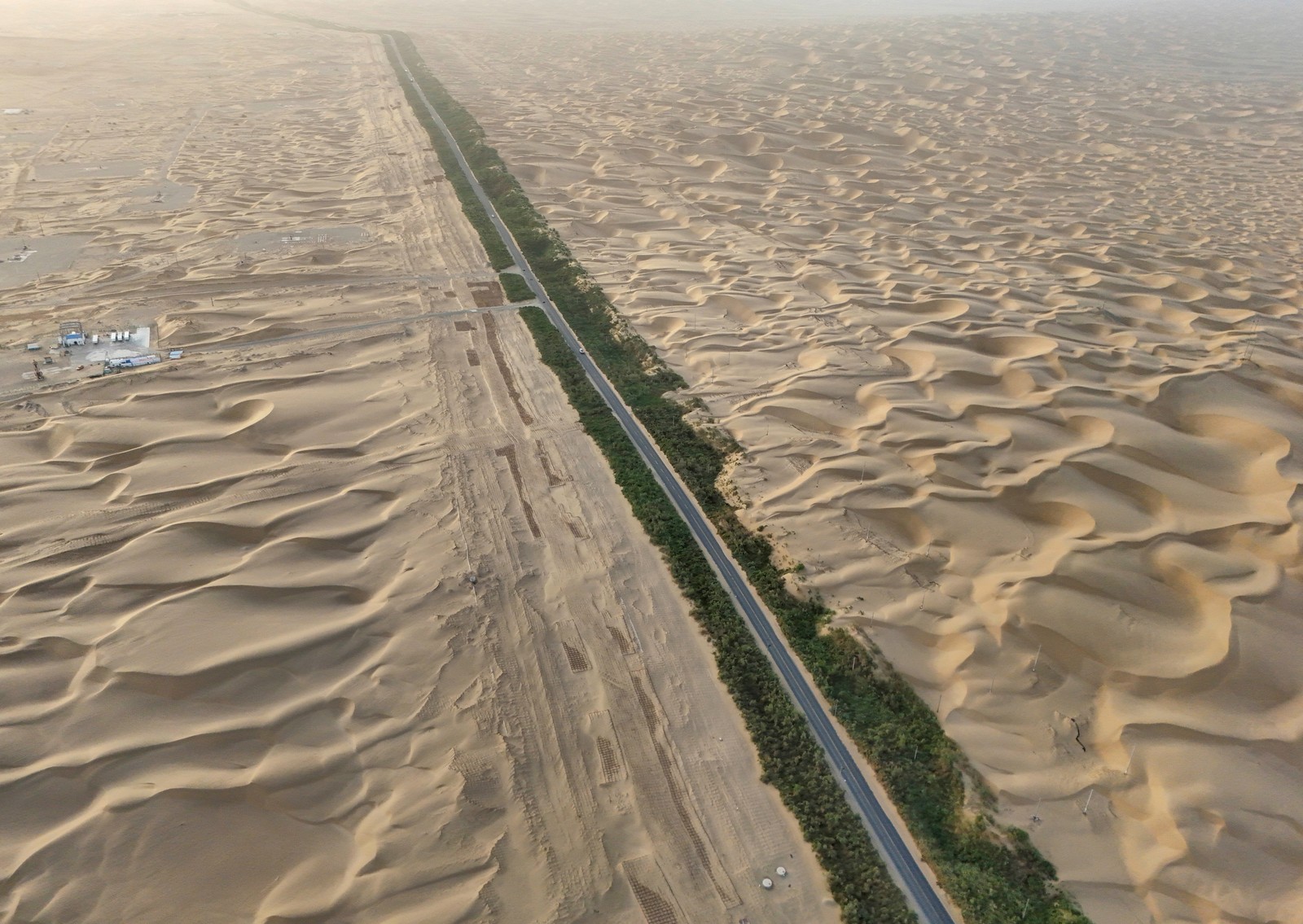 An aerial view of a highway running through a desert of sand dunes