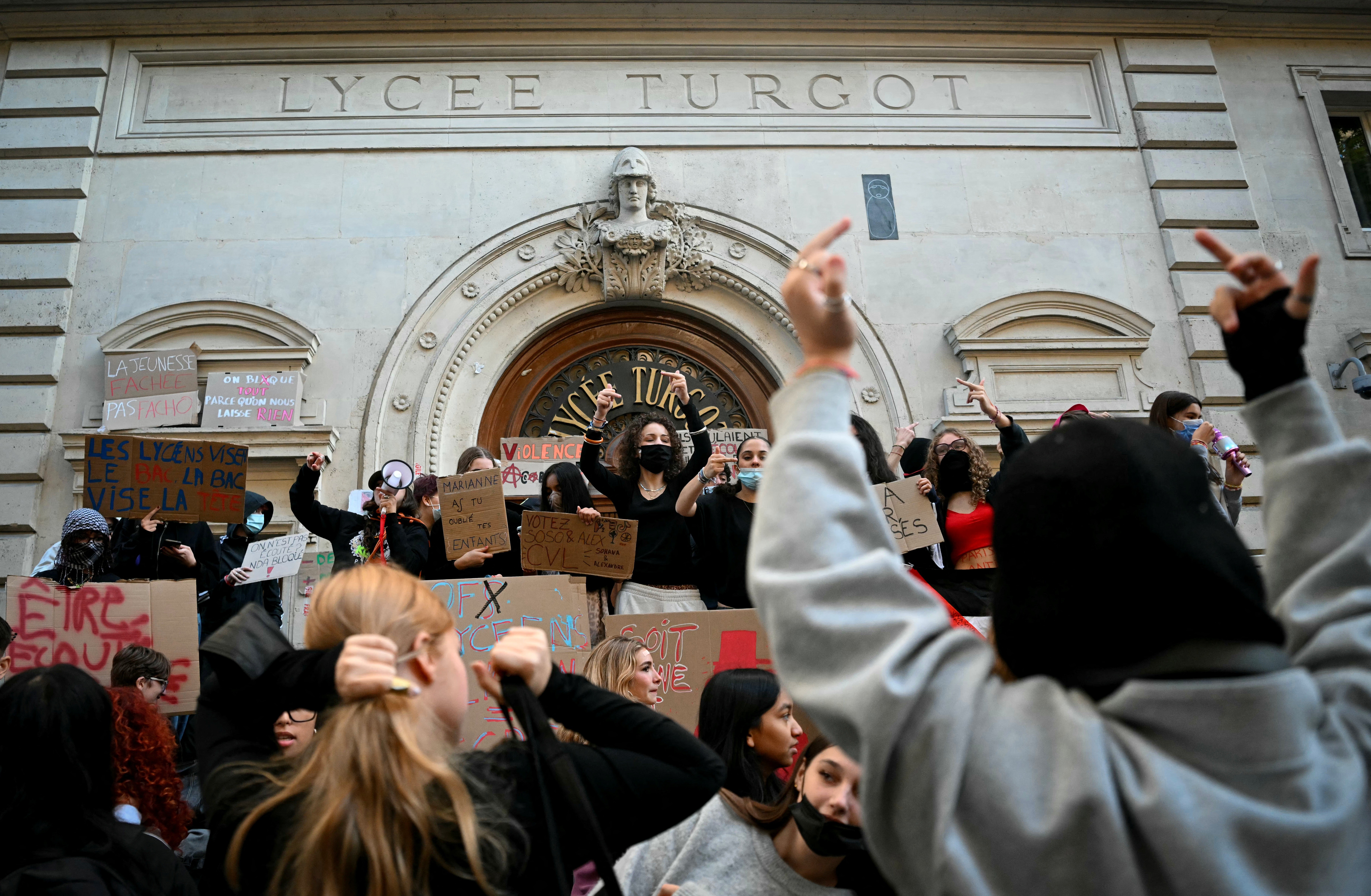 Protesting students gather and hold placards as they blockade part of a school.