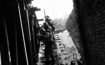 black-and-white photo of soldiers aiming weapons, descending open staircase in snow with sky behind