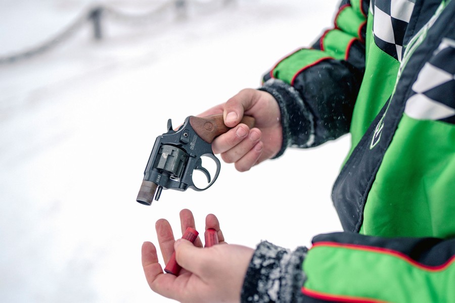 A person holds a starter pistol while standing on a snowy road.