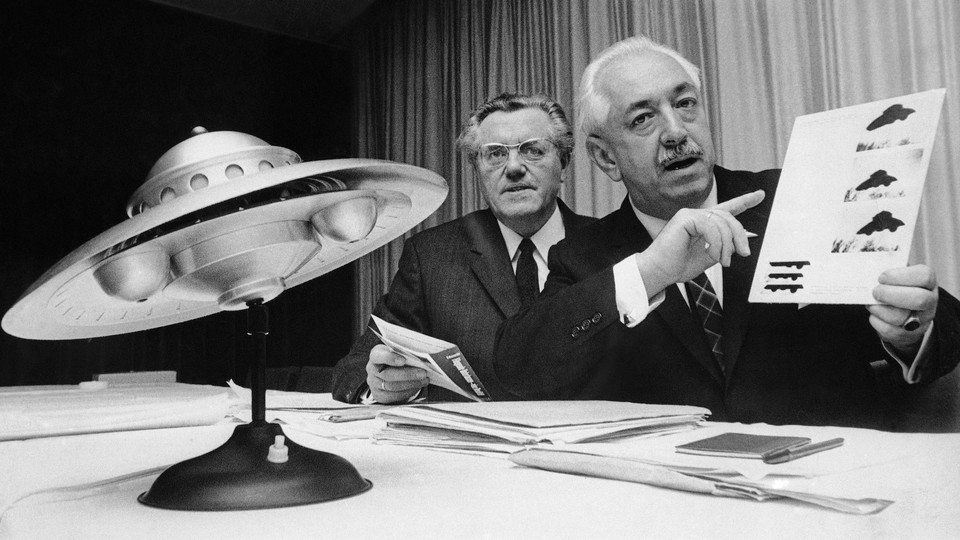 Officials speak at a news conference about UFOs in Germany in 1967, with a small replica of a flying saucer.