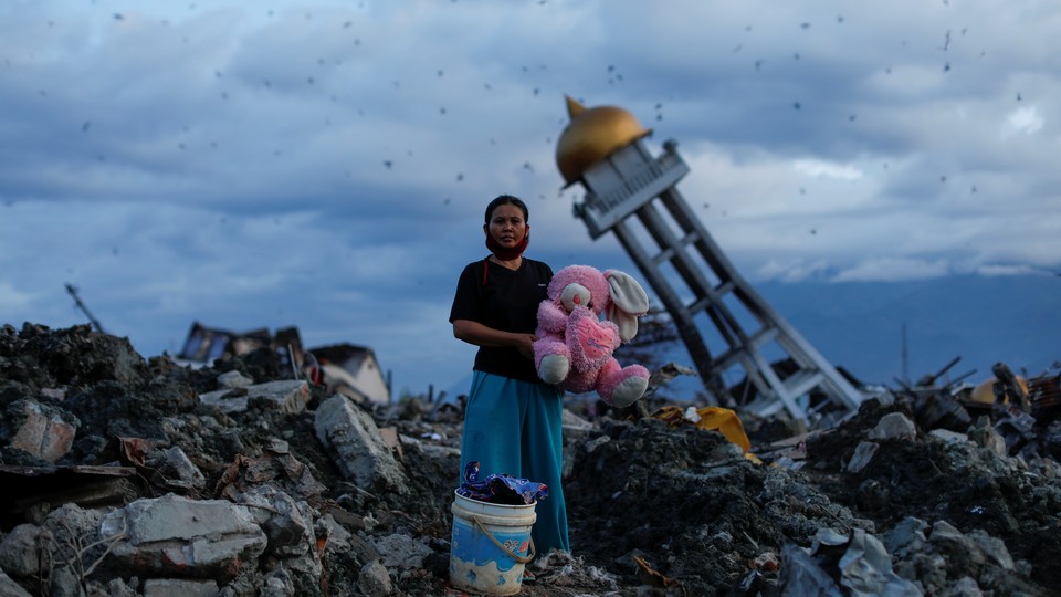A woman holds a stuffed rabbit toy after it was found at her destroyed home where she said she had lost her three children, in Palu, Central Sulawesi, Indonesia.