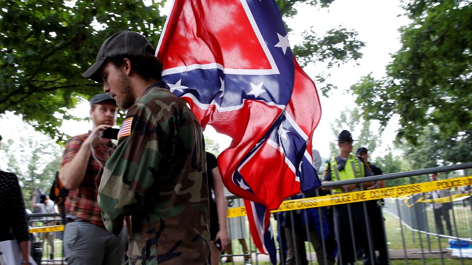 Man in fatigues carrying Confederate flag