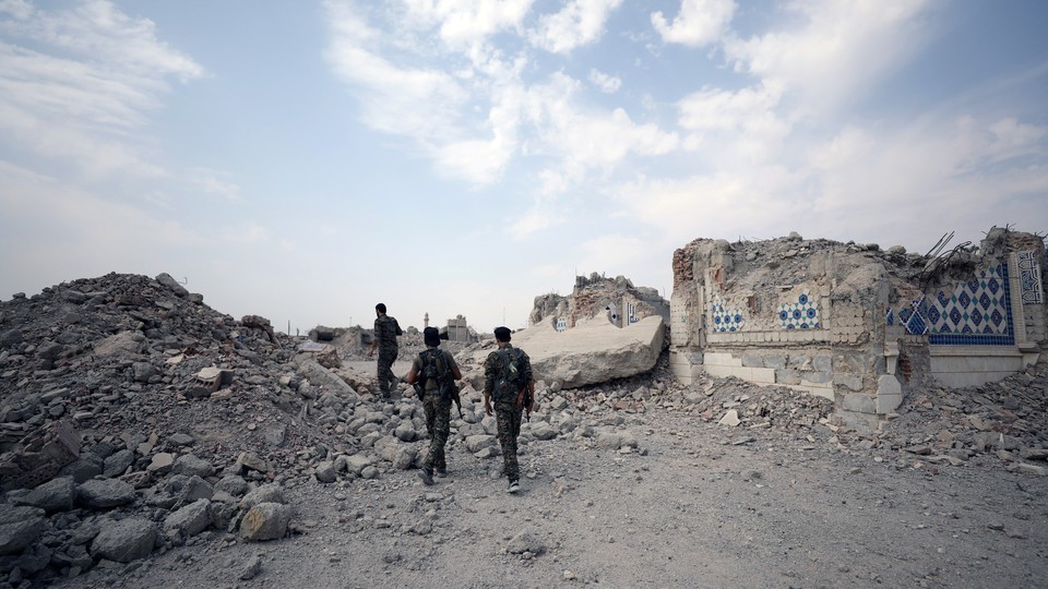 Fighters from Syrian Democratic Forces stand near the destroyed Uwais al-Qarni shrine in Raqqa, Syria.