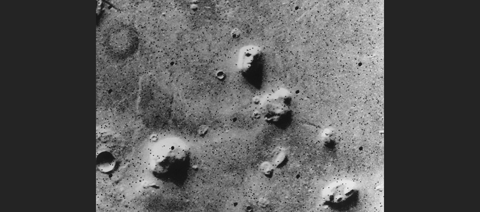 A famous old image of the surface of Mars, seen from orbit, with one rock formation appearing to resemble a human face