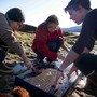 Teacher leader Jamie Karlson shows Natalie Carter (left) and Paris Knuteson (right) how to prepare sea cucumbers for cooking.