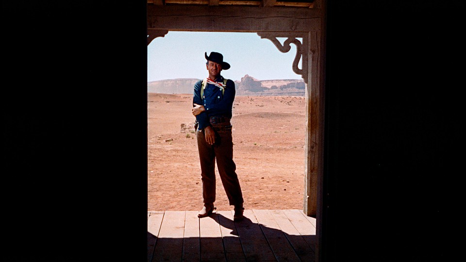 John Wayne stands alone in a doorway