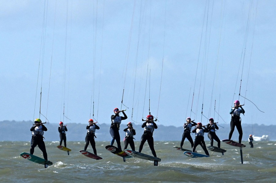 About a dozen people race while kitesurfing, all airborne at the same time.