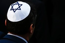 A man wearing a white yarmulke with a blue Star of David