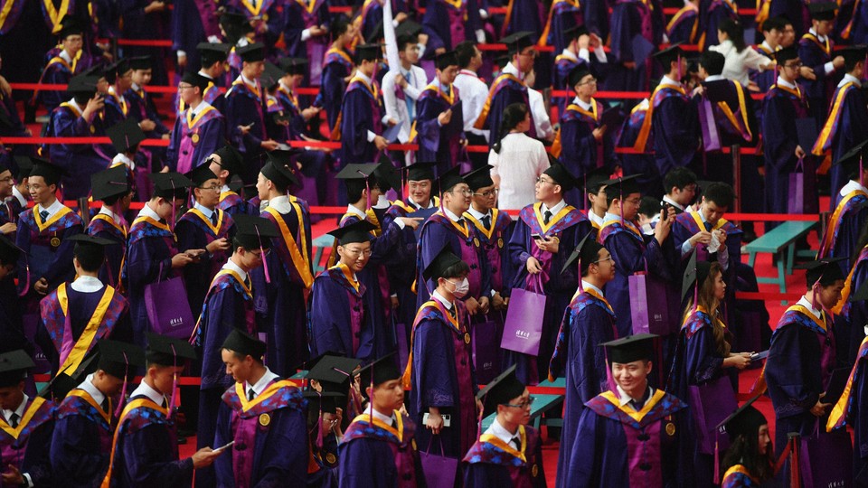 Tsinghua University graduates attend their commencement ceremony in caps and gowns.