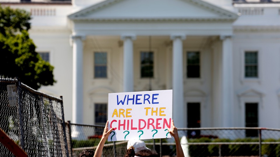 A protester holding a sign that reads "Where are the children?" in front of the White House.