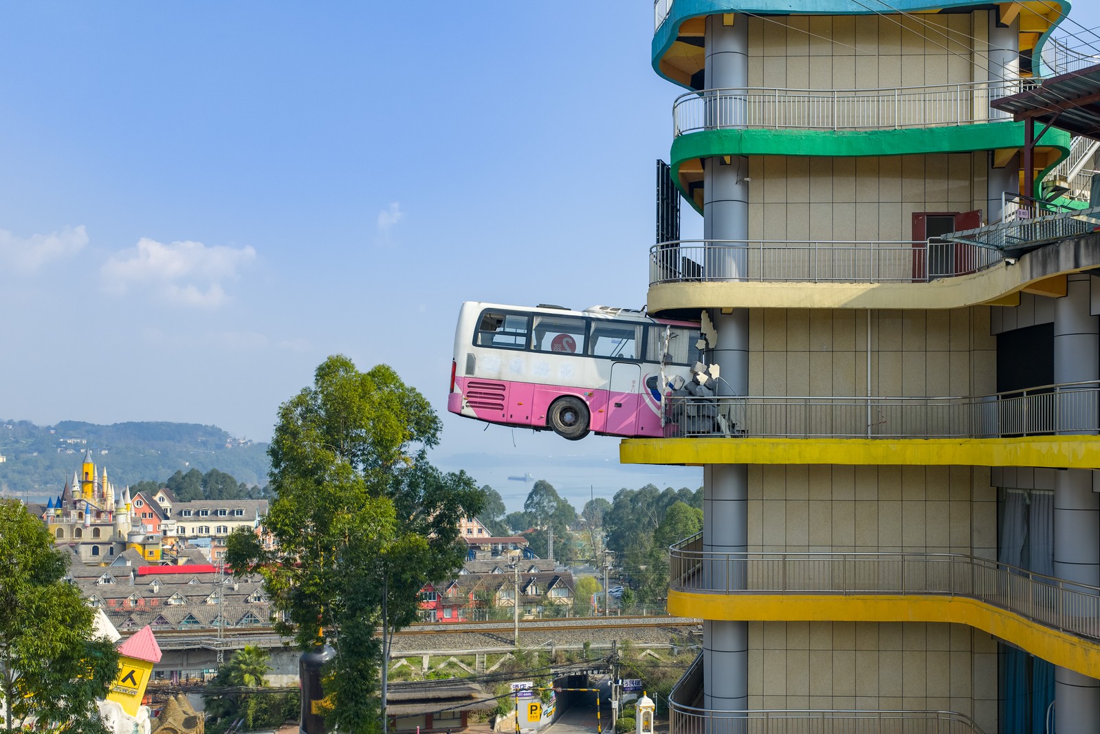 An art installation features a bus bursting through an upper-story wall of a building.