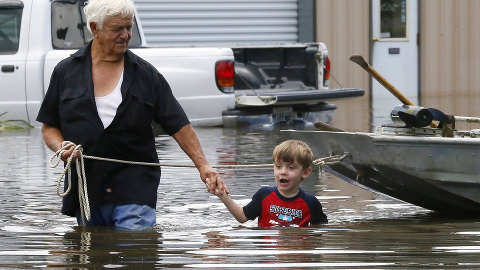 Richard Rossi and his 4 year old great grandson, Justice, wade through water in search of higher ground.