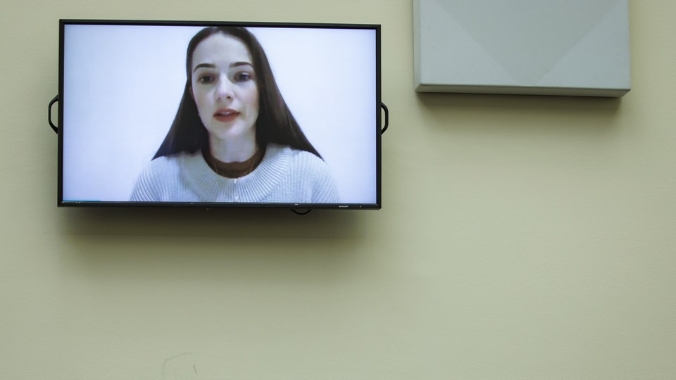 A TV screen showing the face of Oleksandra Matviychuk, as if on a video-call