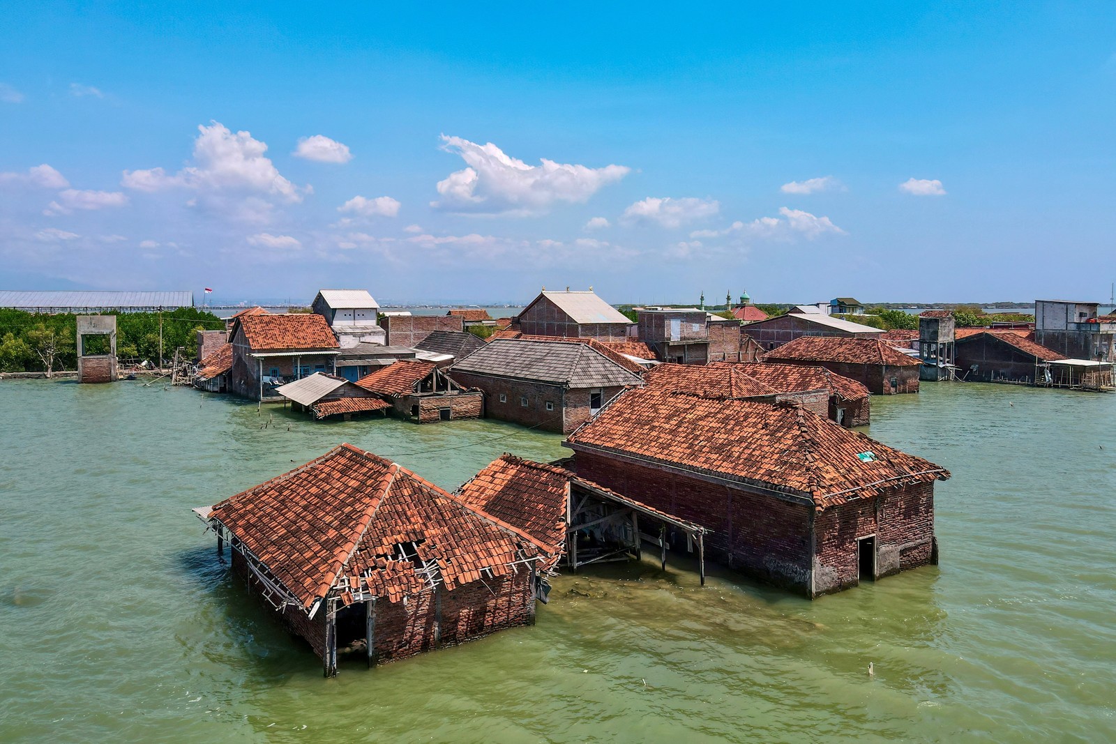 An aerial view of a cluster of flooded and abandoned houses
