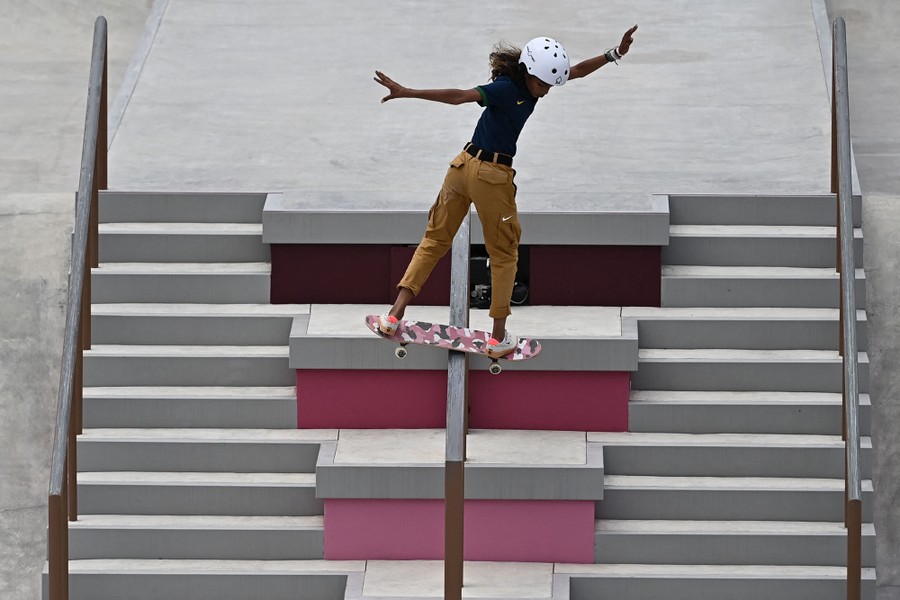 A young skateboarder rides a rail in a skate park.