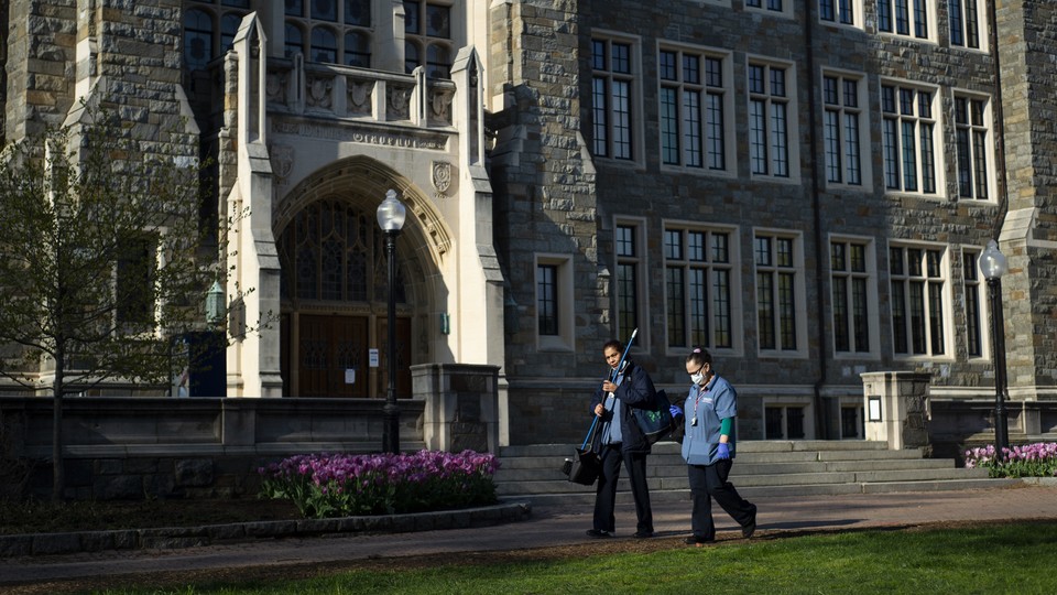 Georgetown University workers walk across campus with cleaning supplies