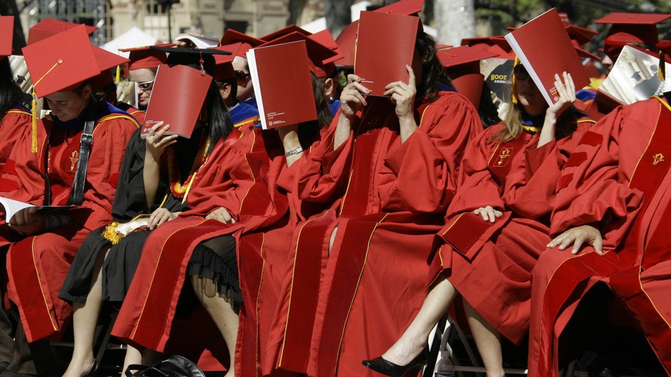 Women in graduation gowns covering their faces