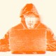 An orange-scale illustration of a hooded person with eyes blurred out, typing into a laptop.