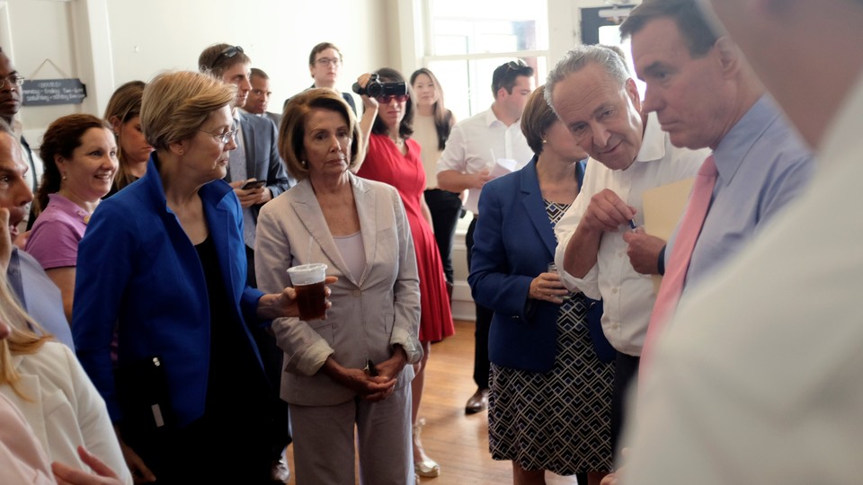 Nancy Pelosi and Elizabeth Warren stand in a room with others.