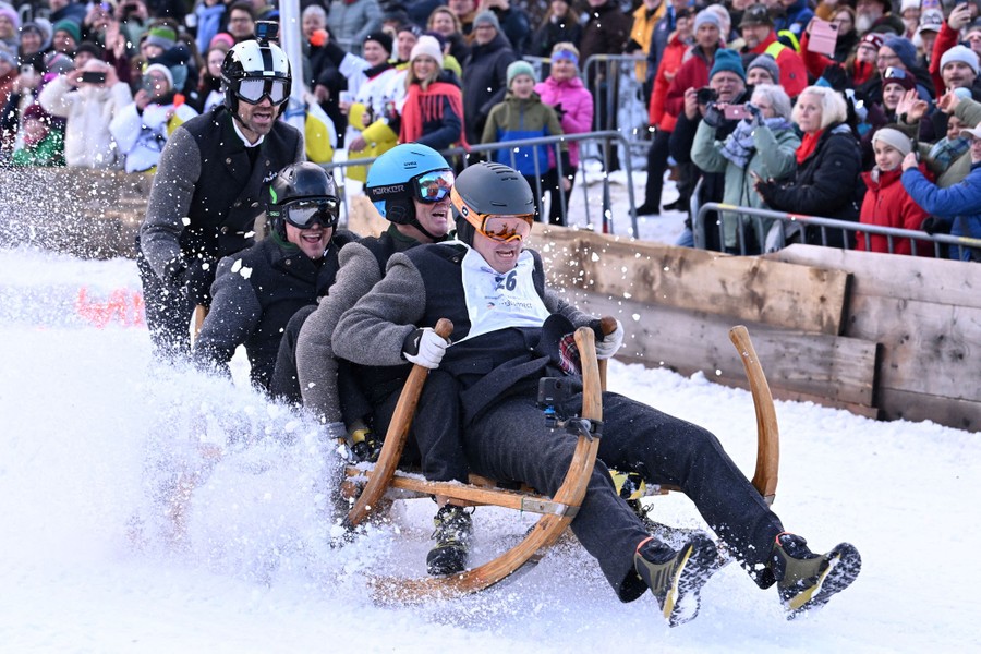 A team of four people rides a traditional wooden sled in a race.