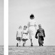 two black-and-white photos with a white strip between them; one of a father and children, the other of a mother and the same children