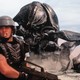 A scene from "Starship Troopers" with a large bug-like alien and some troopers with guns