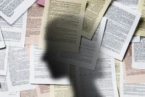 A shadow of a woman against a wall of legal papers