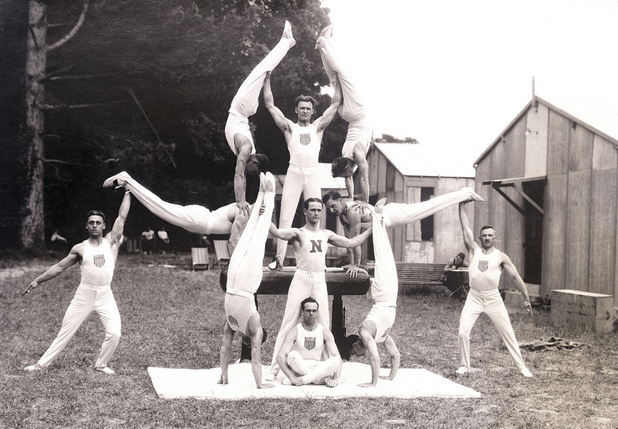 A team of 11 gymnasts pose in varying difficult stances, forming a symmetric scene.