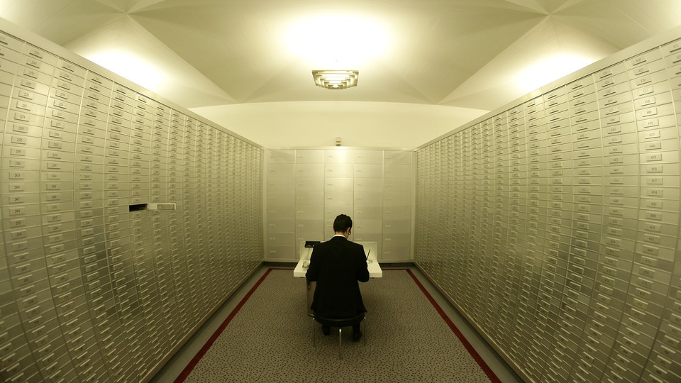 An employee sits amongst safe boxes in a safe room at a Swiss bank