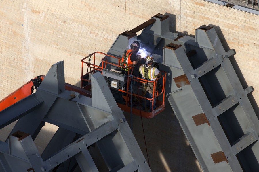 Two welders in a lift work on a large steel structure.