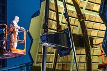 A picture of a technician examining the James Webb Space Telescope and its gold-covered mirrors