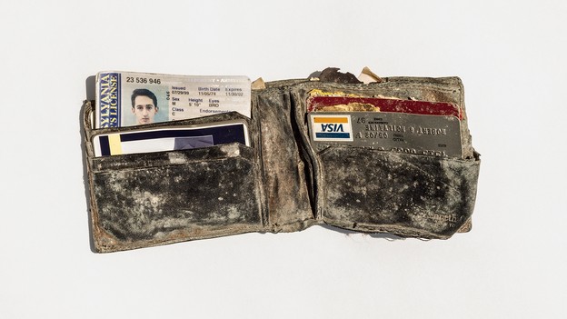 Dusty wallet containing ID, credit card, and other items