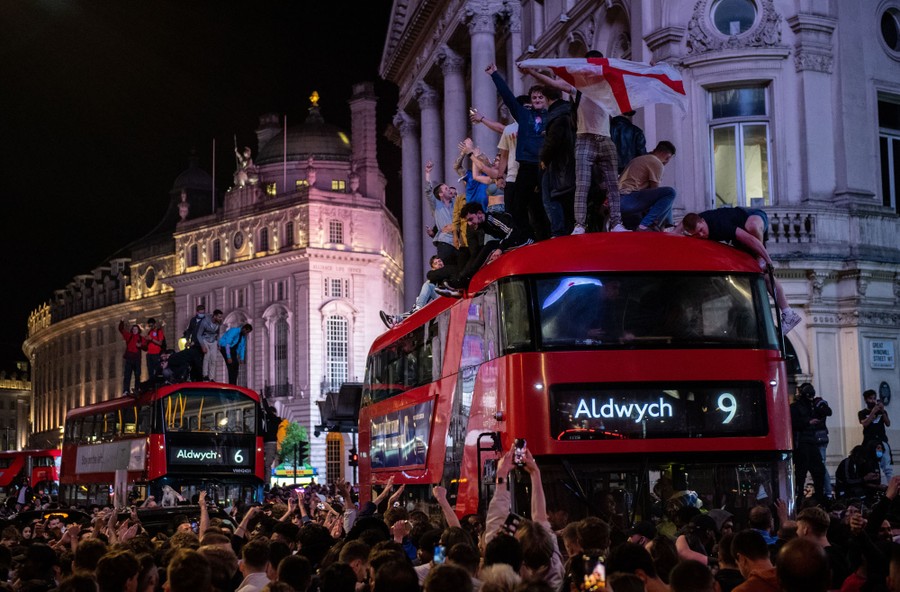 Soccer fans celebrate in the streets of London, and on top of double-decker buses.