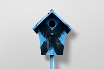 Photo-illustration of a blue birdhouse with a black "X" painted on it