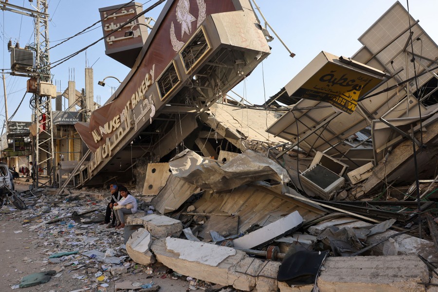 A man and his son sit surrounded by devastation.
