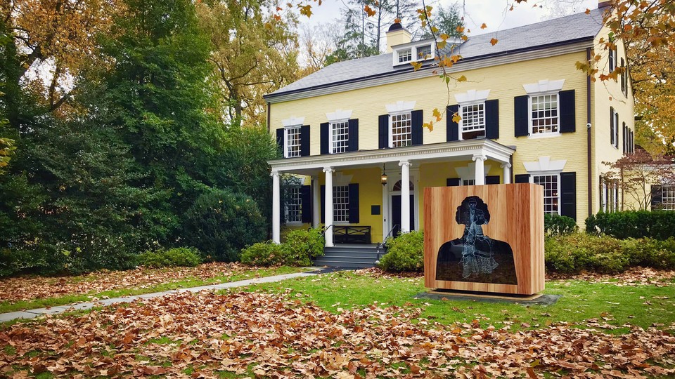 A sculpture of a bust with several image layers stands in front of a campus building at Princeton. 