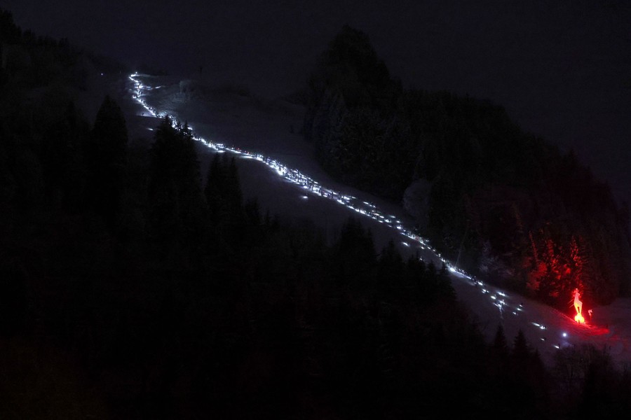 A night view of competitors racing up a ski slope.