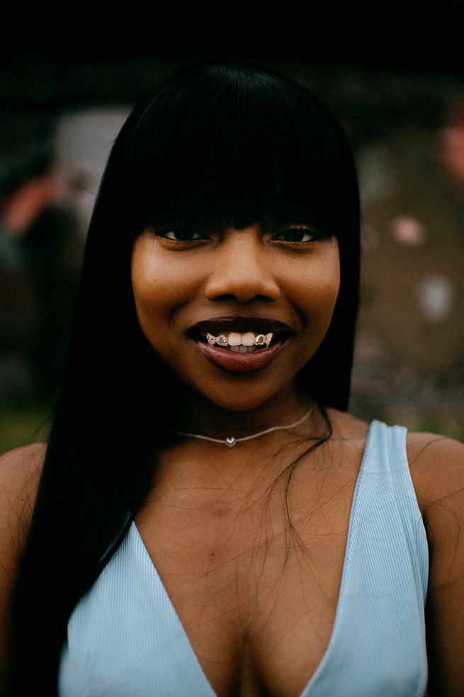 A woman in blue shows her gold teeth