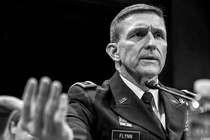 Fotografía en blanco y negro de Michael Flynn en uniforme testificando ante el Congreso con un micrófono.