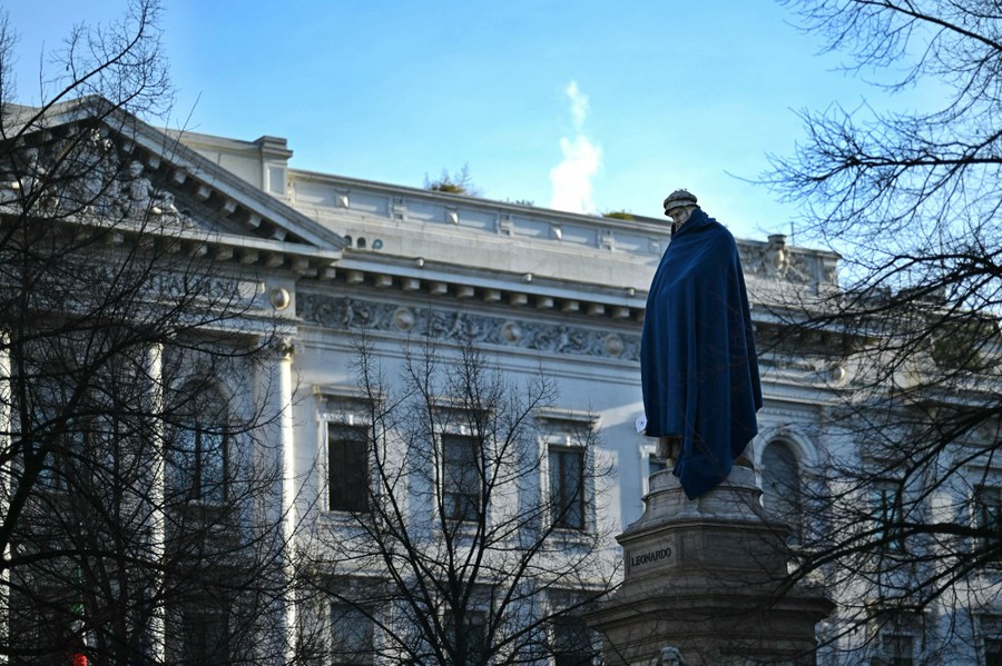 A statue in a public square is covered in a blue blanket.