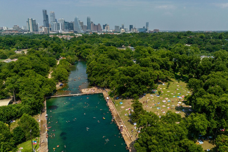 People gather in a city park to swim in a large pool.