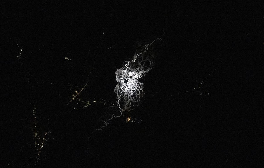 A braided riverbed seen in reflected moonlight at night.