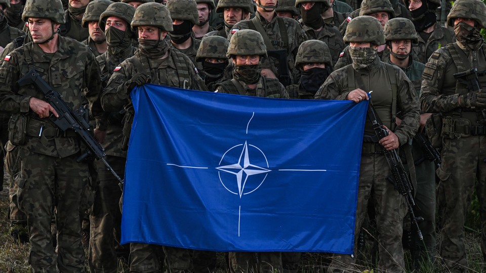 A group of Polish soldiers hold a NATO flag at a training in Orzysz, Poland, in July 2022.