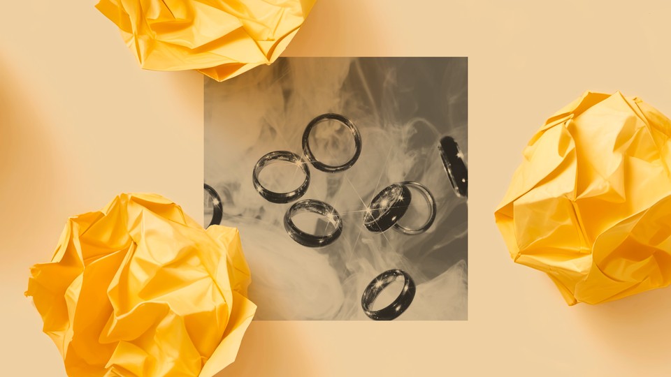 A black-and-white photo shows several shiny wedding bands displayed on a marbled surface.