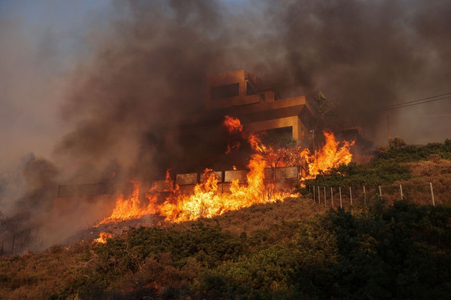 Flames engulf a house on a hillside.
