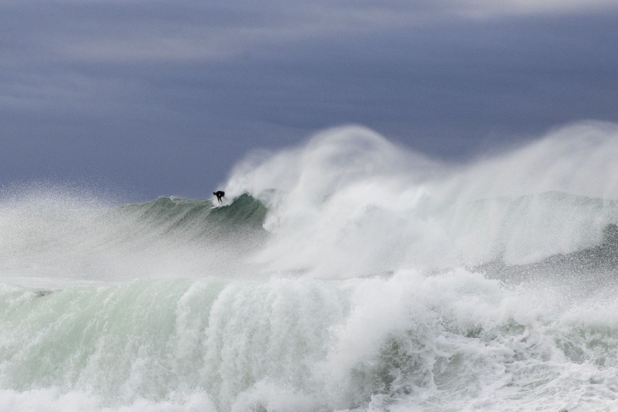 A surfer rides a large wave in wild surf conditions.