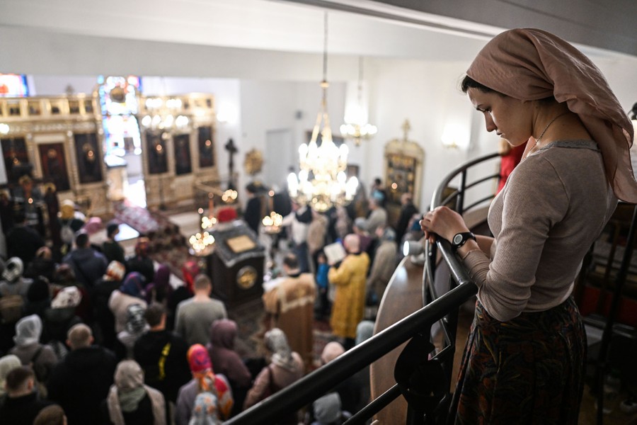 A small crowd of people prays inside a church.