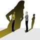 The large, elongated shadow of a woman falls on a nervous-looking man who is speaking to another man